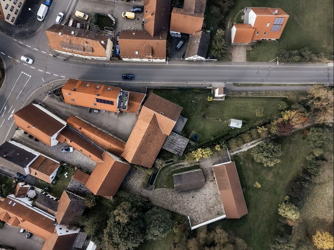 Luftaufnahme eines Wohngebiets mit roten Dächern und Straßen