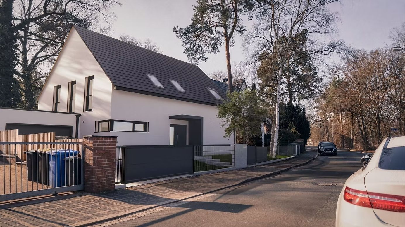 Modernes Haus an einer ruhigen Straße mit Bäumen.