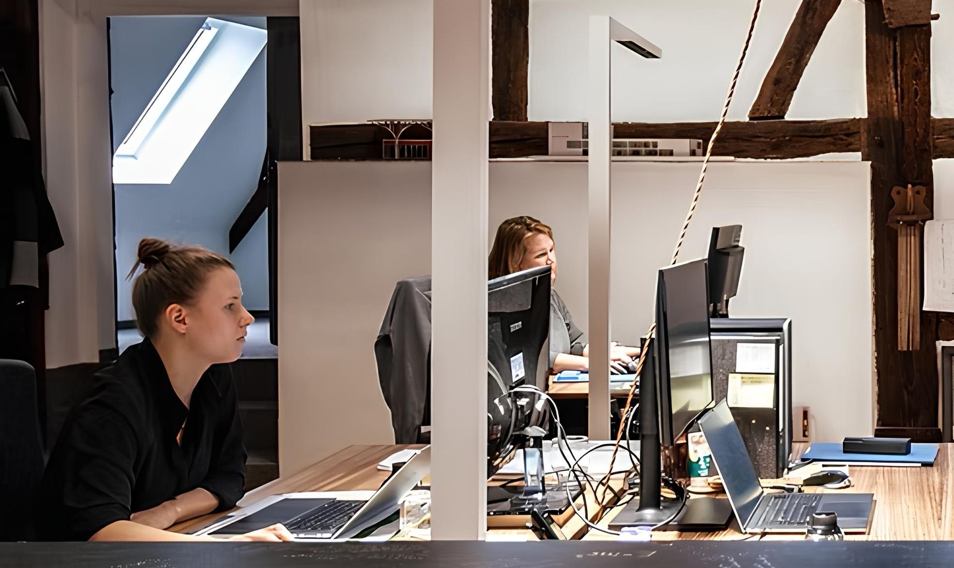 Blick auf ein Büro mit Holzdecke und zwei Frauen, die am Computer arbeiten