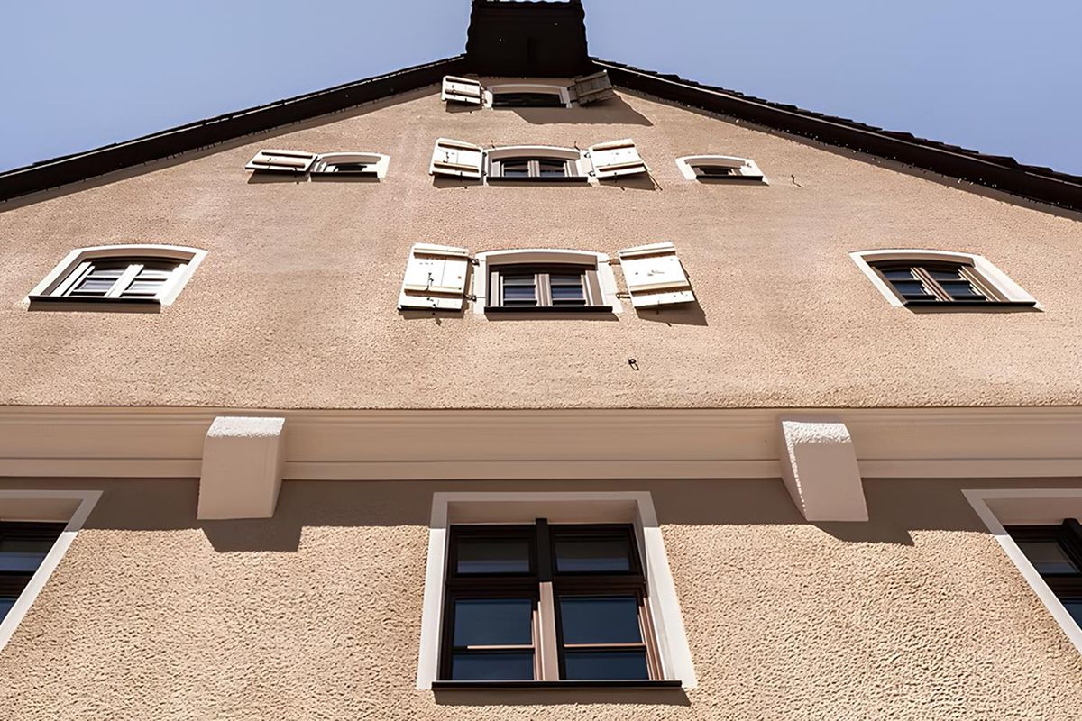 Ansicht einer Hausfassade von unten mit offenen Fensterläden